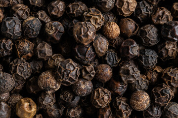Una imagen macro de bolas de pimienta negra que muestra su textura rugosa y detalles intensos. Captura la esencia especiada de este ingrediente fundamental en la cocina.