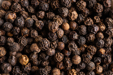 Una imagen macro de bolas de pimienta negra que muestra su textura rugosa y detalles intensos. Captura la esencia especiada de este ingrediente fundamental en la cocina.