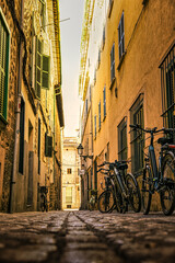 Una calle estrecha de estilo antiguo en Mallorca, con bicicletas apoyadas contra la pared y...