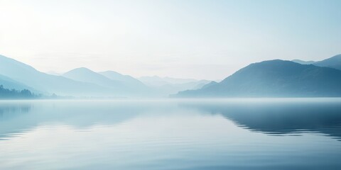 Tranquil lake reflects misty mountain range.