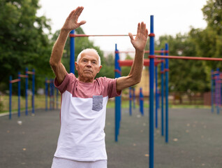 Elderly man doing gymnastic exercises in park