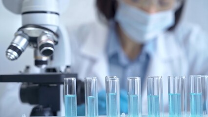 Test tubes with a blurred scientist in a lab coat in the background