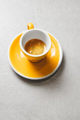 Yellow Espresso Cup Filled With Rich Coffee on Gray Table With Ample Free Space 