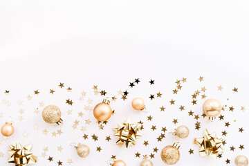 Festive flat-lay arrangement featuring golden Christmas ornaments, glittery baubles, and star-shaped confetti