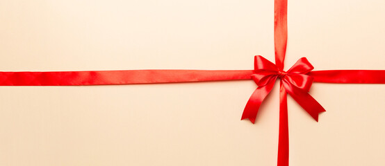 Top view of Red ribbon rolled and red bow isolated on colored background. Flat lay with copy space