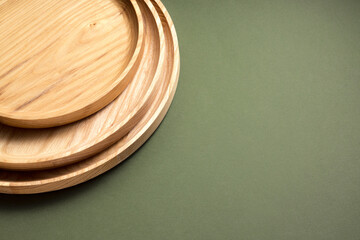 Wooden flat plates on a green background. The concept of ecological tableware. Products for modern kitchen. Zero emissions.