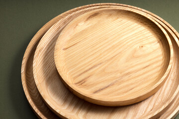 Wooden flat plates on a green background. The concept of ecological tableware. Products for modern kitchen. Zero emissions.
