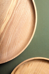 Wooden flat plates on a green background. The concept of ecological tableware. Products for modern kitchen. Zero emissions.