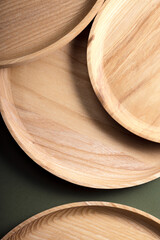 Wooden flat plates on a green background. The concept of ecological tableware. Products for modern kitchen. Zero emissions.