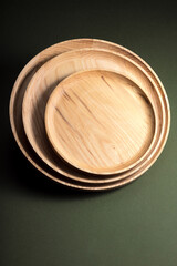 Wooden flat plates on a green background. The concept of ecological tableware. Products for modern kitchen. Zero emissions.