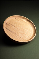 Wooden flat plates on a green background. The concept of ecological tableware. Products for modern kitchen. Zero emissions.