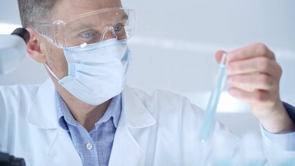 Scientist researcher with protective glasses and mask examining