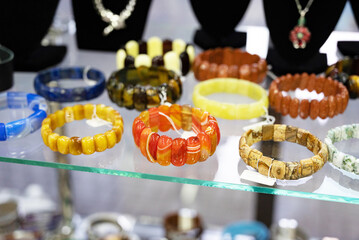 Assorted gemstone bracelets displayed on a glass shelf.
