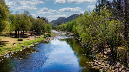 Landscape view of Santa Rosa river going trough Calamuchita small town. Large green trees in both sides
