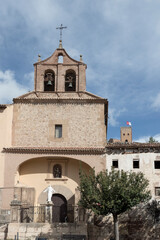 Historic church facade with bell tower and statue under a clear blue sky in a traditional village.