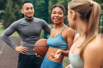 Group of multiracial women and man wearing sportwear talking, training together outdoors