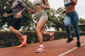 Closeup, active, fit athlete wearing sportwear running together outdoors. Sport, motivation concept