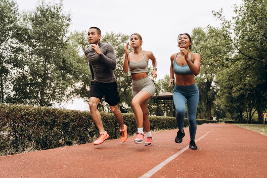 Concentrated multinational women and man running together on the street. Sport, motivation concept