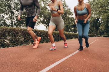 Closeup, diverse group of young athlete wearing sportwear running together on the street