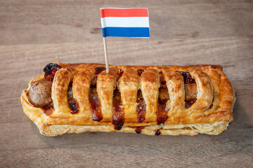 Frikandelbroodje with dutch flag, a typical dutch savoury snack consisting of a puff pastry roll with a minced meat sausage and curry sauce inside