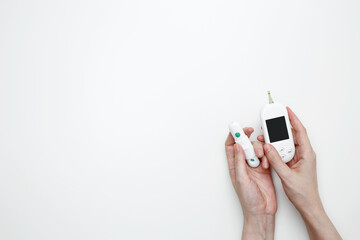 Female hands holding glucometer for measuring blood glucose levels,  lancet. Concept of worldwide diabetes awareness