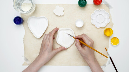 A woman paints clay products. Hobby clay modeling