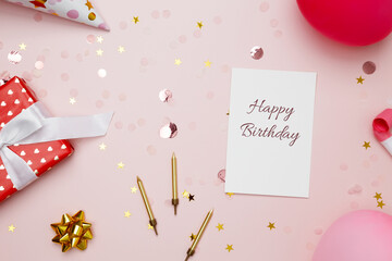 Birthday card surrounded by colorful balloons, party hats, candles, and confetti. Concept of festive birthday celebrations