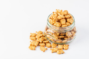 Glass jar full of fish-shaped crackers  isolated on white background with copy space