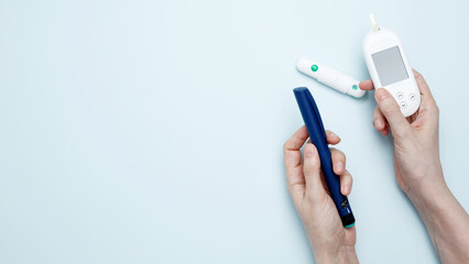 Female hands holding glucometer for measuring blood glucose levels,  lancet. Concept of worldwide diabetes awareness