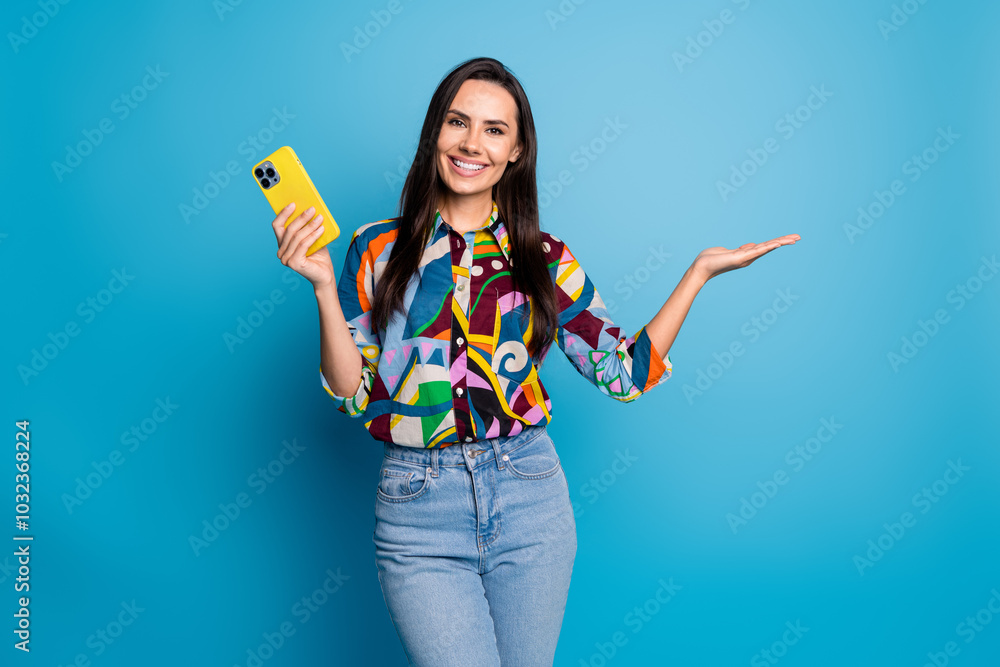 Poster portrait of positive girl dressed print blouse hold smartphone palm presenting object empty space is