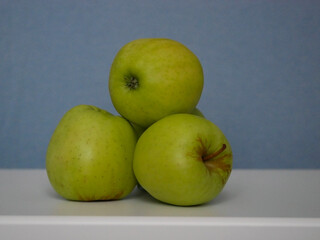 Golden Delicious apples at a blue background