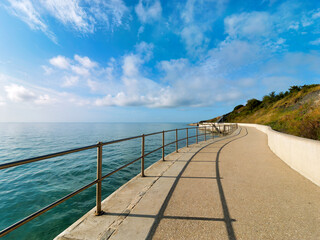 A 390 metre seawall construction built to protect further erosion and stabilise the cliffs along the  coastline east of Lyme Regis in Dorset captured on a sunny day with soft fluffy clouds