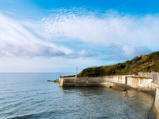 A 390 metre seawall construction built to protect further erosion and stabilise the cliffs along the  coastline east of Lyme Regis in Dorset captured on a sunny day with soft fluffy clouds