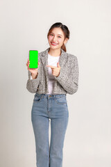 Smiling young Asian business woman leader entrepreneur wearing stylish suit holding blank screen mobile phone on isolated background.