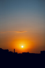 A beautiful and gentle dawn. The sun rises over the dark rooftops of the big city, creating a peaceful and quiet morning.