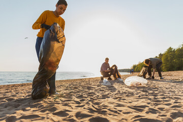 Earth day. Volunteers activists collects garbage cleaning of beach coastal zone. Woman and mans...