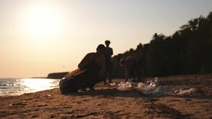Earth day. Volunteers activists collects garbage cleaning of beach coastal zone. Woman and mans puts plastic trash in garbage bag on ocean shore. Environmental conservation coastal zone cleaning