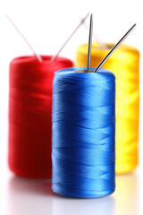 Colorful spools of thread with needles ready for sewing on a bright surface