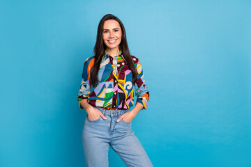 Photo portrait of pretty young girl hands pockets posing wear trendy colorful print outfit isolated on blue color background