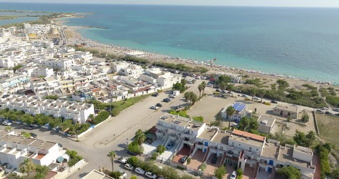 Aerial view of Torre Mozza beach in Salento, Puglia, Italy. There are people in the water and on the beach. In the background a coastal tower. Holiday concept.