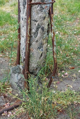The old, worn-out concrete oratory is broken at its base near the ground, revealing rusty rebar and...