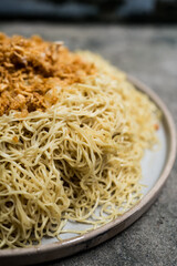 Yellow noodles in plate sprinkle with fried garlic. Egg yellow noodles