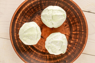 Sweet delicious pear marshmallow with ceramic saucer on wooden table, macro, top view.