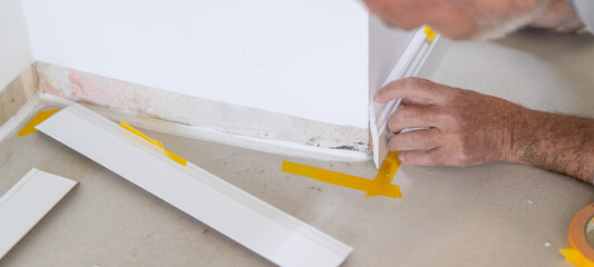 Man installing new skirting board - DIY home work concept