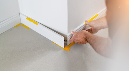 Man installing new skirting board - DIY home work concept