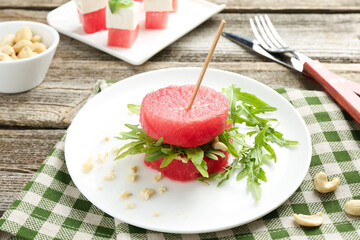 Tasty appetizer with watermelon, cashews and arugula on wooden table