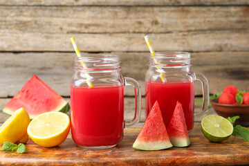 Tasty watermelon drink in mason jars and fresh fruits on wooden table