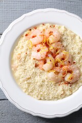 Delicious risotto with shrimps and cheese on grey wooden table, top view
