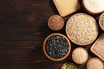 Different types of cereals, seeds and legumes on wooden table, flat lay. Space for text