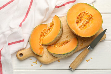 Cut ripe Cantaloupe melon and knife on white wooden table, flat lay